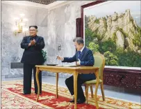  ?? SOUTH KOREA PRESIDENTI­AL BLUE HOUSE VIA AP ?? South Korean President Moon Jae-in writes on a visitor’s book as North Korean leader Kim Jong Un stands at the northern side of Panmunjom in North Korea.