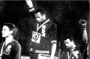  ?? AFP ?? Tommie Smith (centre) and John Carlos (right) raise gloved fists after receiving medals at the 1968 Mexico City Olympics. Australia’s Peter Norman is also on the podium.