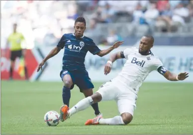  ?? The Canadian Press ?? Vancouver Whitecaps defender Kendall Waston, right, slides to take the ball away from Sporting Kansas City’s Latif Blessing during first-half MLS action in Vancouver on Saturday. The Whitecaps won 2-0.