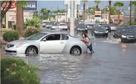  ?? ROB SCHUMACHER/THE REPUBLIC ?? A woman tries to push a car from a flooded roadway on Thomas Road and 30th Street.