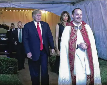  ?? DAMON HIGGINS / THE PALM BEACH POST ?? President Donald Trump and first lady Melania Trump are led into Bethesda-by-the-Sea Episcopal Church in Palm Beach by the Rev. James Harlan as they attend the late-night Christmas Eve service.