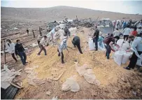 ?? MAJDI MOHAMMED THE ASSOCIATED PRESS ?? Palestinia­ns collect grain after Israeli troops with bulldozers and heavy equipment destroyed a storage structure in Khirbet Humsu in Jordan Valley in the West Bank on Friday.