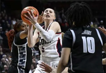  ?? Jessica Hill/Associated Press ?? UConn guard Paige Bueckers, center, cuts between Georgetown center Ariel Jenkins, left, and forward Mya Bembry, right, during the first half Monday of the finals of the Big East Conference tournament at Mohegan Sun Arena in Uncasville, Conn.