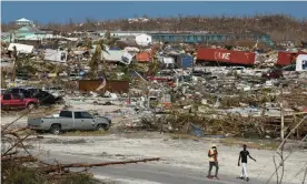  ??  ?? Men walk past damage in the wake of Hurricane Dorian in Marsh Harbour, Great Abaco, Bahamas. Photograph: Loren Elliott/Reuters