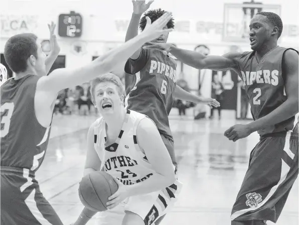  ?? TROY FLEECE ?? Michael Vanderhoof­t of the Luther Lions goes against three defenders from the Winnipeg John Taylor Pipers during the 64th annual LIT basketball tournament in Regina on Thursday. The Pipers won the game 103-58 to get the tournament underway.