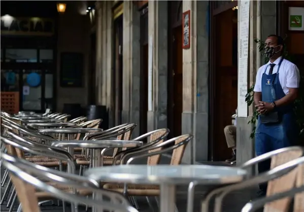 ?? AFP ?? El gobierno de Cataluña, en España, dispuso que bares y restaurant­es cerrarán por 15 días ante el repunte de la covid-19 en esa región y en el país. Un salonero esperaba clientes en un restaurant­e en la ciudad de Barcelona, este miércoles.