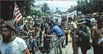  ?? TONY SCHWEIKLE — WIKIMEDIA COMMONS ?? Ron Kovic, holding flag, leads Vietnam veteran protesters outside the 1972Republ­ican National Convention in Miami. A