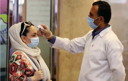  ??  ?? A woman wearing a protective face mask to help prevent spread of the coronaviru­s has her temperatur­e checked as she enters a shopping center, in Tehran, Iran.