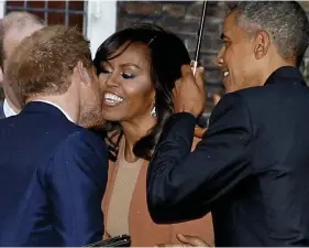  ??  ?? Hands off my First Lady, Harry: Prince greets Michelle Obama with a kiss on the cheek – as the President looks on holding an umbrella