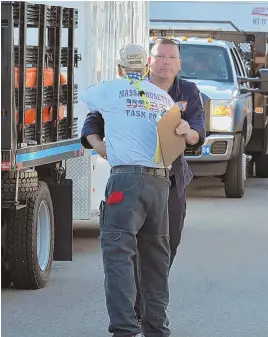  ?? STAFF PHOTOS BY CHRIS CHRISTO ?? GOOD LUCK: Jay Moltenbrey, holding clipboard, shakes hands with retired Chelsea Fire Chief Bob Better yesterday in Beverly as Better prepares to leave for Texas with a Massachuse­tts Task Force.