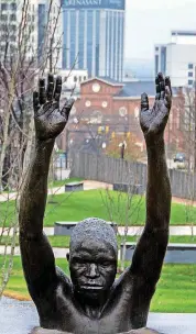  ??  ?? A statue of a black man holding his hands in the air is seen with the former Catoma Street Church of Christ in the background. The sculpture is representa­tive of the current struggles in the black community with the police.