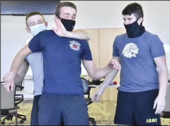  ?? Staff photo/Teresa Dowling ?? Cadet Parker Maurer begins a takedown of Cadet Justin Miller while TJ Burrows looks on during a hands-on class on Saturday. The trio are part of the current police academy at Wright State University — Lake Campus.