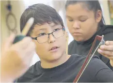  ??  ?? Zack Sanderson prepares his bow in St. Michael’s fiddle class on Tuesday.