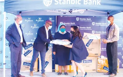  ??  ?? Stanbic Bank CEO Josh Tapambgwa hands over personal protective equipment worth US$ 200 000 to St Anne’s Hospital representa­tive Sister Mary and Solidarity Trust trustee Ms Karen Mutasa while Stanbic chairman Greg Sebborn (left) and head of marketing and corporat e affairs Palmer Mugavha (right) look on.