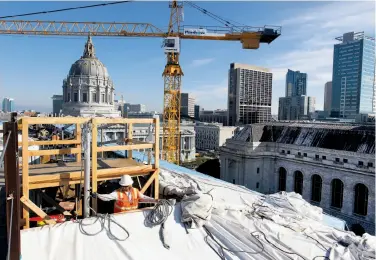  ?? Paul Chinn / The Chronicle ?? A constructi­on crew, part of the largest-growing job sector, works atop S.F.’s War Memorial building.