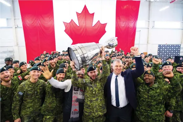  ?? JONATHAN HAywARD/THE CANADIAN PRESS ?? Cpl. Cody Williamson of Smithers, B.C., hoists the Grey Cup alongside CFL commission­er Randy Ambrosie on Tuesday at CFB Edmonton.