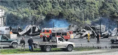  ?? PHOTO:MARK PRICE ?? Fish oil factory gutted . . . Fire crews mop up the twisted metal remains of an aircraft hangar, an engineerin­g workshop and a fish oil factory burnt to the ground at Neils Beach, South Westland, yesterday.