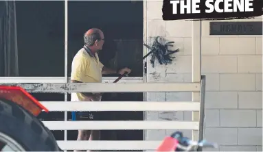  ?? Picture: ALIX SWEENEY ?? Dean Webber's uncle Ian Webber washes away the fingerprin­t dust on the Webber family’s Topton St home at Alva Beach where two men were fatally stabbed on Monday morning.