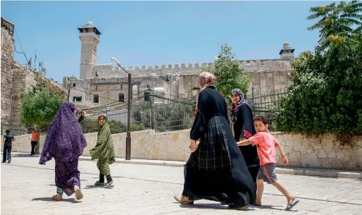  ?? AFP ?? Palestinia­ns walking by outside the Cave of the Patriarchs, also known as the Ibrahimi Mosque, which is a holy shrine for Jews and Muslims, from the Palestinia­n side in the heart of the divided city of Hebron in the West Bank on Friday. Unesco has...