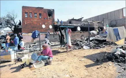  ?? PICTURES: ITUMELENG ENGLISH ?? DEVASTATIO­N: A woman washes her laundry outside a flat which caught fire in Marlboro on Saturday night. One-year-old Simphiwe Ndinisa died due to smoke inhalation and about 1 000 people have been displaced after 120 shacks caught fire.