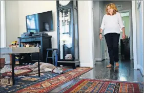  ??  ?? Bonnie Sakallaris, 67, walks from her first-floor master bedroom to the open-concept living room and kitchen in her home in the Railroad Cottages community.