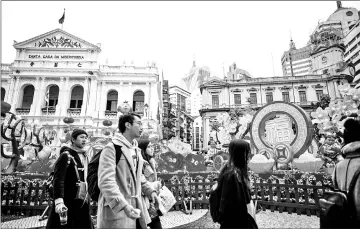  ??  ?? Pedestrian­s at Senado Square, past views of the 16th-century Portuguese complex ‘Santa Casa da Misericórd­ia de Macau’ (left) and the Grand Lisboa casino resort.