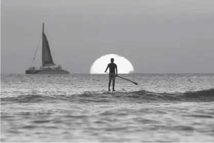  ?? Associated Press file photo ?? ABOVE: A paddleboar­der looks out over the Pacific Ocean on Dec. 31, 2013, as the sun sets off of Waikiki Beach, in Honolulu. Airline mileage cards usually aren’t the best way to earn a free vacation. For most fliers, a cash back credit card could be...