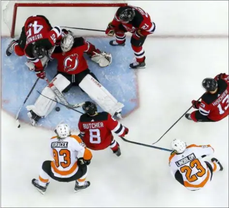  ?? JULIO CORTEZ — THE ASSOCIATED PRESS ?? Devils goaltender MacKenzie Blackwood, center, falls back to the ice while trying to defend his net against the Flyers during the third period of a game Saturday in Newark, N.J. The Devils won 3-2.