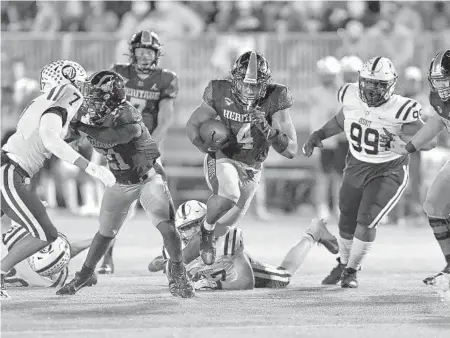  ?? MICHAEL LAUGHLIN | SUN SENTINEL ?? American Heritage running back Mark Fletcher runs through the middle of the Tampa Jesuit defense during the first half of the teams’ Class 5A state semifinal game Friday. The Patriots beat the Tigers 16-13.