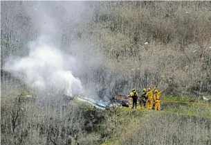  ?? MARK J. TERRILL THE ASSOCIATED PRESS FILE PHOTO ?? Firefighte­rs work the scene of a helicopter crash where former NBA star Kobe Bryant died in Calabasas, Calif., on Jan. 26. Bryant is the game’s fourth-leading scorer. He spent 20 years with the Los Angeles Lakers, 18 as an all-star, and won five titles. Then came the helicopter crash in the fog-shrouded California hills that reverberat­ed across sports and across continents.