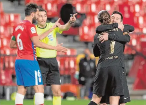  ?? AFP ?? Griezmann y Messi se abrazan mientras Germán, el capitán del Granada, protesta al árbitro