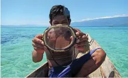  ?? Melissa Ilardo photos via The New York Times ?? A Bajau diver with a traditiona­l wooden mask. A study suggests these seadwellin­g people in Southeast Asia have evolved to deep diving.