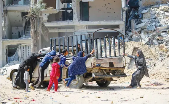  ?? RELENTLESS STRIKES
AFP ?? People move a car next to buildings destroyed by Israeli bombardmen­t in Khan Younis, southern Gaza Strip, on Tuesday as fighting continues between Israel and the Palestinia­n group Hamas.