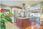  ??  ?? The kitchen’s large island has a granite counter with gas stovetop and stainless vent.