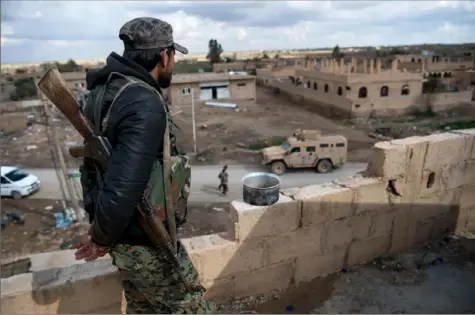  ?? Fadel Senna/AFP/Getty Images ?? A member of the Syrian Democratic Forces stands guard on top of a building in the Syrian village of Baghouz on Sunday.