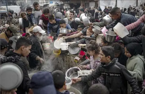  ?? Fatima Shbair/Associated Press ?? Palestinia­ns line up for a meal Thursday in Rafah, Gaza Strip. A report says the risk of famine is “increasing each day.”