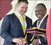  ??  ?? President Cyril Ramaphosa presents the Order of Ikhamanga in Silver to former Springbok rugby captain John Smith.