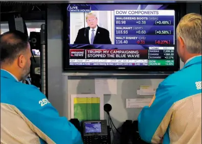  ?? AP/RICHARD DREW ?? Specialist­s on the floor of the New York Stock Exchange watch President Donald Trump’s news conference Wednesday. Major U.S. stock indexes soared Wednesday.