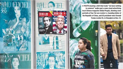  ??  ?? A YOUTH wearing a shirt that reads “we have nothing in common” walks past a news stand advertisin­g local Chinese magazine Global People, showing cover portraits of Sun Yat-sen (center L), founding father of the Republic of China, and US president-elect...