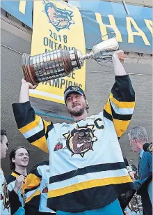  ?? JOHN RENNISON THE HAMILTON SPECTATOR ?? Justin Lemcke raises the J. Ross Robertson Cup below the just unveiled banner at the city hall rally.