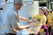  ?? Doug Walker / Rome News-Tribune ?? Analyn Raposo (right), an Armuchee third-grader, recoils slightly Thursday as DNR Fisheries technician James Woolsey hands her a net with a 13-inch lake sturgeon.