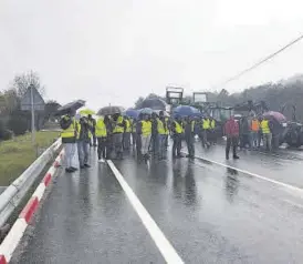  ?? EL PERIÓDICO ?? Los manifestan­tes de Valencia de Alcántara cortan la carretera bajo la lluvia.