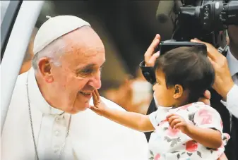  ?? Pablo Martinez Monsivais / Associated Press ?? A child, who was carried out from the crowd to meet Pope Francis, reaches out to touch the pontiff's face during a parade on his way to celebrate Sunday Mass in Philadelph­ia.