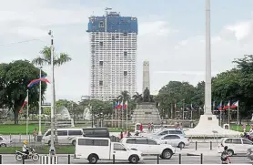  ??  ?? The 49-storey Torre de Manila high-rise condominiu­m looms in the background as seen from the Jose Rizal tomb and monument at Luneta Park in Manila. — AFP