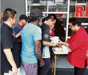  ??  ?? Uma (far right) giving out food packets to the homeless and needy.