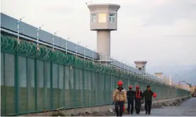  ??  ?? Workers at the perimeter fence of what is officially known as a vocational skills education centre in Xinjiang. Photograph: Thomas Peter/Reuters