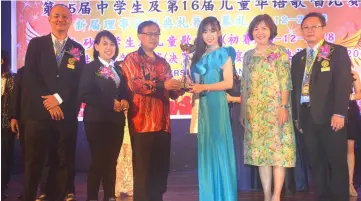  ??  ?? Jamit presents a trophy to Lee Jia Zin, who won the secondary school category of the competitio­n. Looking on are (from left) Cheng, Chua, Tiong and Wee.