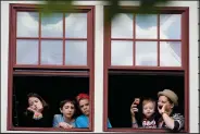  ?? (AP/Steve Helber) ?? Kids watch the proceeding­s from the windows of a garage Sunday as Democratic gubernator­ial candidate Terry McAuliffe speaks to supporters at a rally in Richmond, Va.