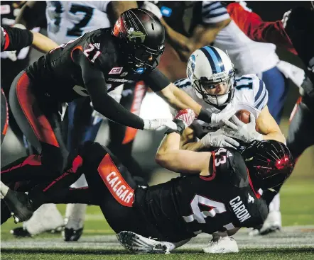  ?? — THE CANADIAN PRESS ?? Toronto’s Devon Wylie is brought down by Stampeders linebacker Max Caron, who was making his CFL debut on Friday night after missing two seasons with torn Achilles tendons.