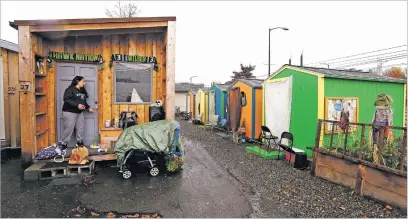 ?? ELAINE THOMPSON/THE ASSOCIATED PRESS ?? Eva Stough opens the door to her tiny house, where she lives with her partner and baby, at a homeless encampment in Seattle. The opposition to tiny houses is often focused on developmen­ts for homeless people.